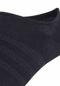 Calcetín de tobillo negro con un diseño texturizado y un puño acanalado. Confeccionado con un material elástico y transpirable para mayor comodidad.