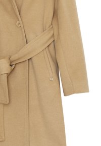 Cappotto cammello con un'ispirazione tessile, vita con cintura e chiusura a un bottone. Presenta una tasca laterale e un accento metallico con il logo.