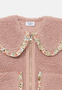 Rosa Fleecejacke mit Reißverschluss, mit blumengemustertem Kragen und Taschen. Weiche Textur, abgerundete Kanten und detaillierte Blumenakzente verbessern das Design.