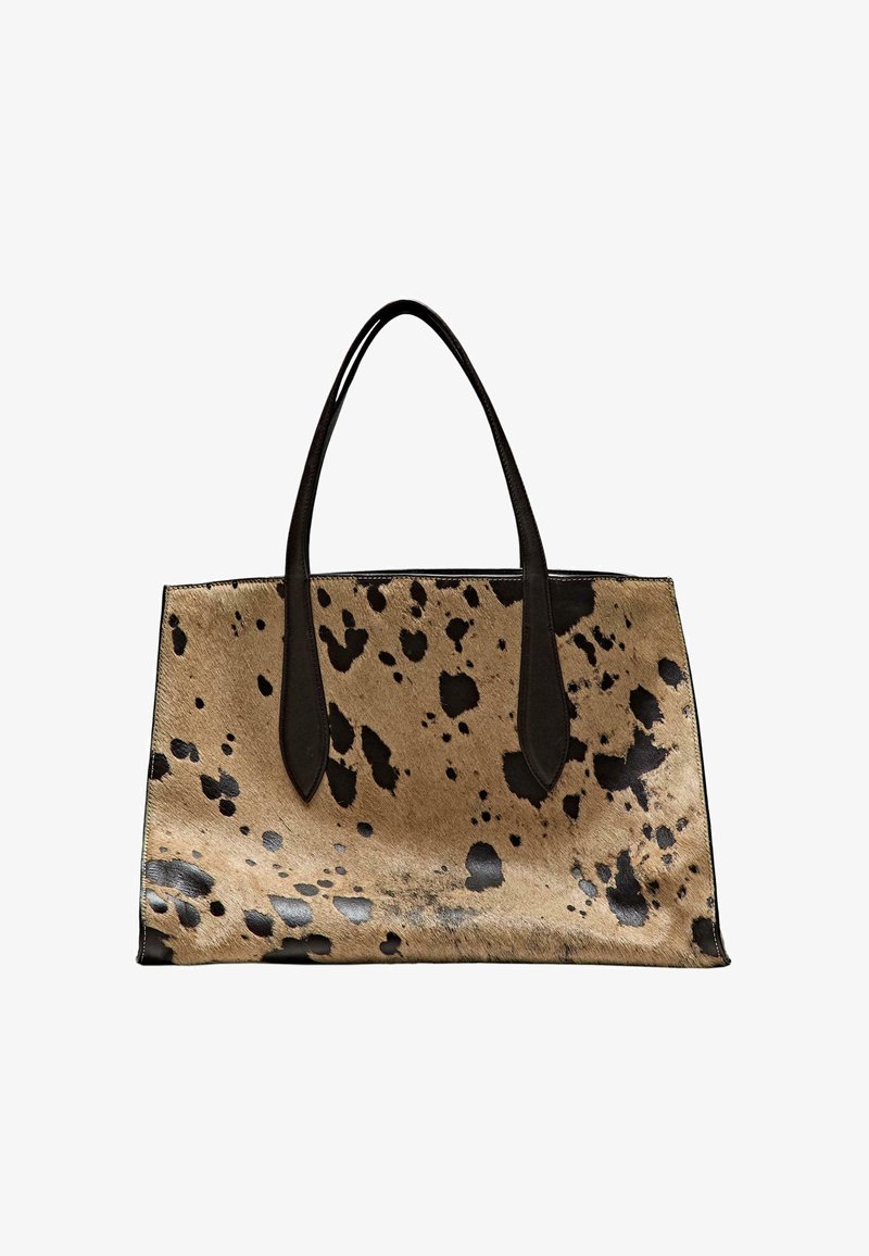 Tote-Bag mit einem beigen und schwarzen gepunkteten Muster. Hergestellt aus einem Material mit Haaren, mit langen schwarzen Ledergriffen und einer strukturierten Form.