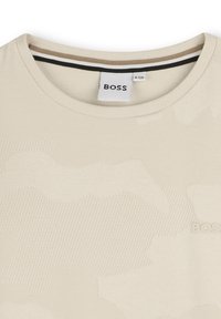 T-shirt beige chiaro con un sottile motivo camouflage testurizzato. Design con colletto a girocollo e etichetta del marchio "BOSS" in grigio chiaro davanti.