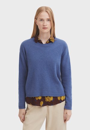 Blue knit sweater with a round neck, long sleeves, and a ribbed hem, layered over a brown shirt featuring yellow floral patterns.