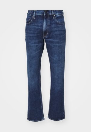 Jeans en denim bleu foncé avec un bas évasé. Les caractéristiques incluent un design à cinq poches, des coutures contrastées et une fermeture à boutons.
