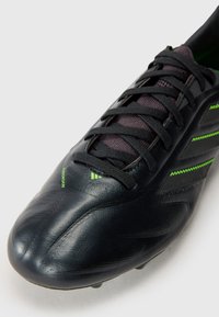 Black soccer cleat with textured leather upper, green accent stripes, and black laces. Features a streamlined design and rounded toe.