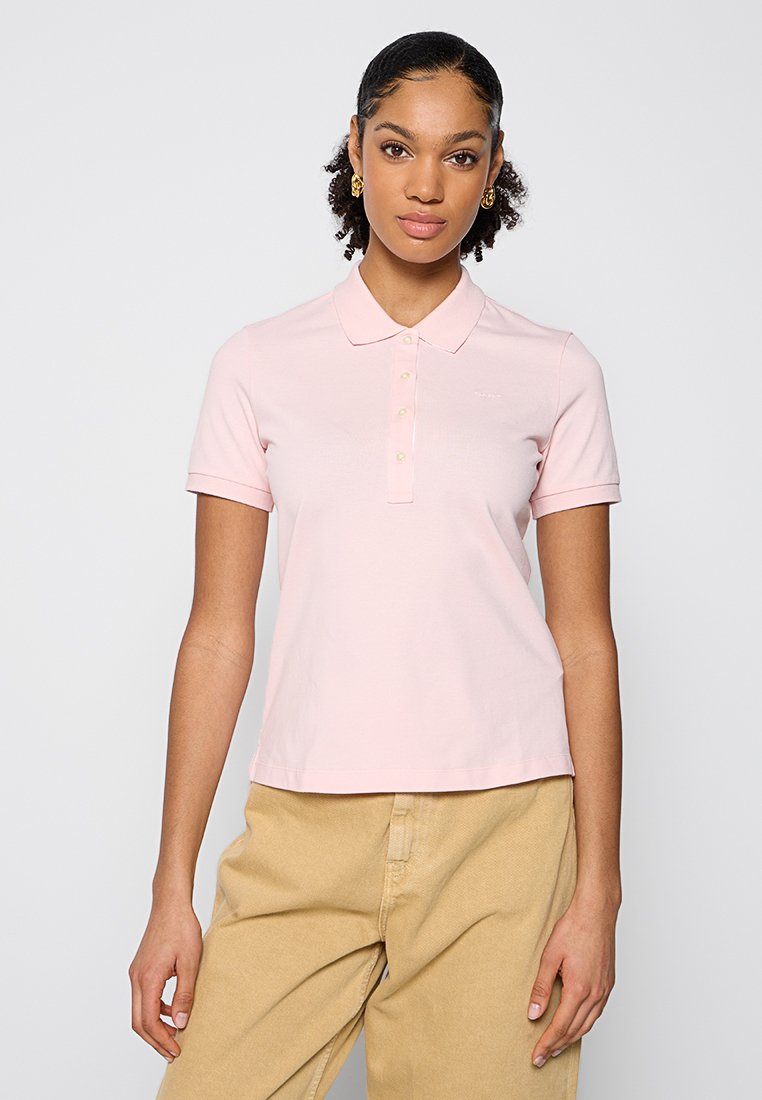 Polo rose à manches courtes avec un col et une patte de boutonnage à trois boutons. Fabriqué à partir d'un tissu doux, avec des détails de marque subtils.