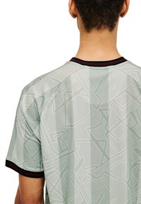 Kortärmad skjorta i ljusgrön, med ett subtilt geometriskt mönster och svarta detaljer vid kragen och ärmarna. Slät textur.