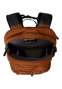 Pomarańczowy plecak z materiału, z zamkiem błyskawicznym, czarnymi paskami i wewnętrzną kieszenią. Zauważalna gładka tekstura i metka logo wewnątrz.