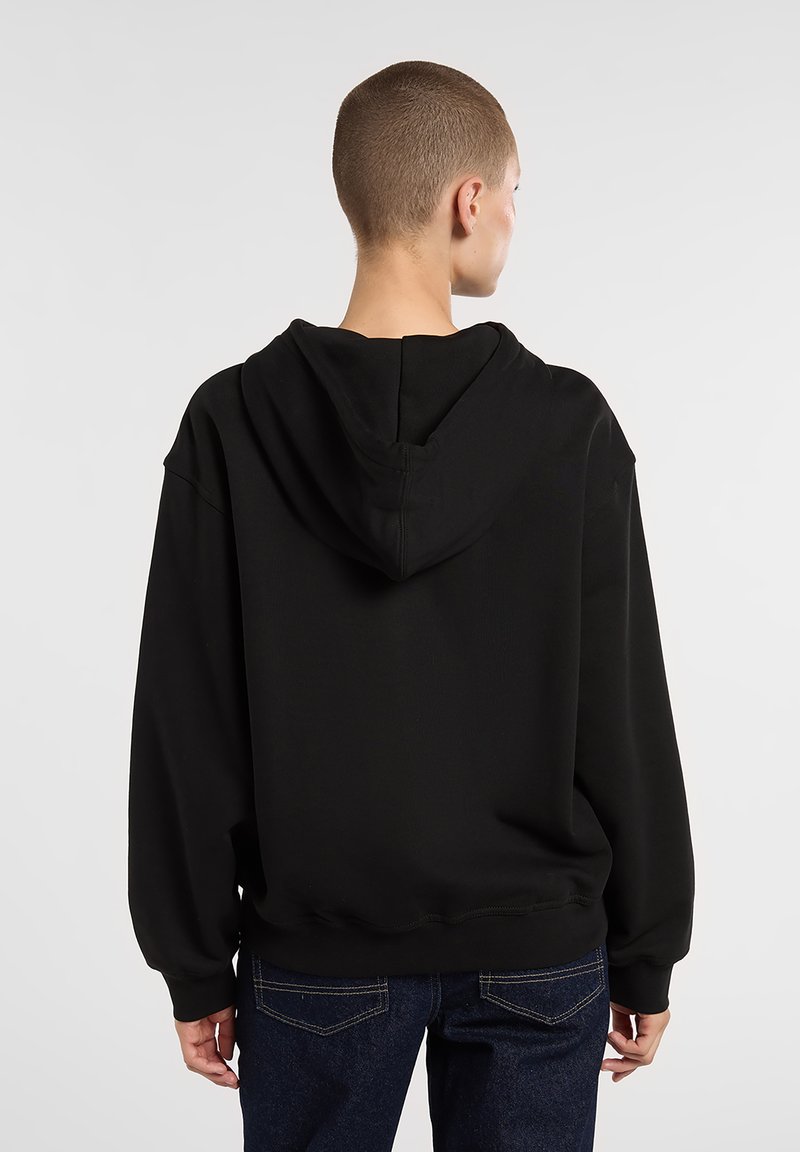 Zwarte hoodie gemaakt van zacht stof, met een grote capuchon, doorlopende schouders en geribbelde manchetten. Eenvoudig ontwerp zonder zichtbare logo's of patronen.