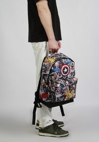 Czarny plecak w motywach komiksowych z grafiką superbohaterów, z przednią kieszenią, regulowanymi szelkami i zaokrąglonym wierzchem.
