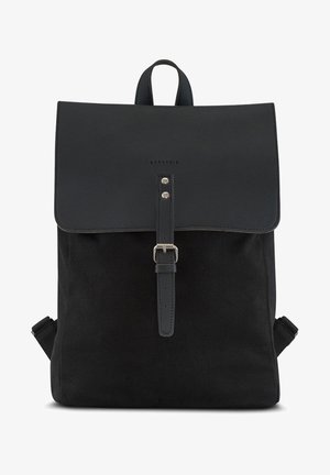 Mochila negra con solapa frontal, cierre de hebilla, asa superior y dos tirantes para los hombros, nombre de la marca "Expatrié" impreso en la solapa.