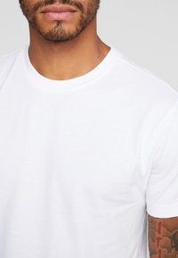 Witte katoenen T-shirt met een ronde hals en korte mouwen, met een gladde textuur en zonder zichtbare patronen of accenten.