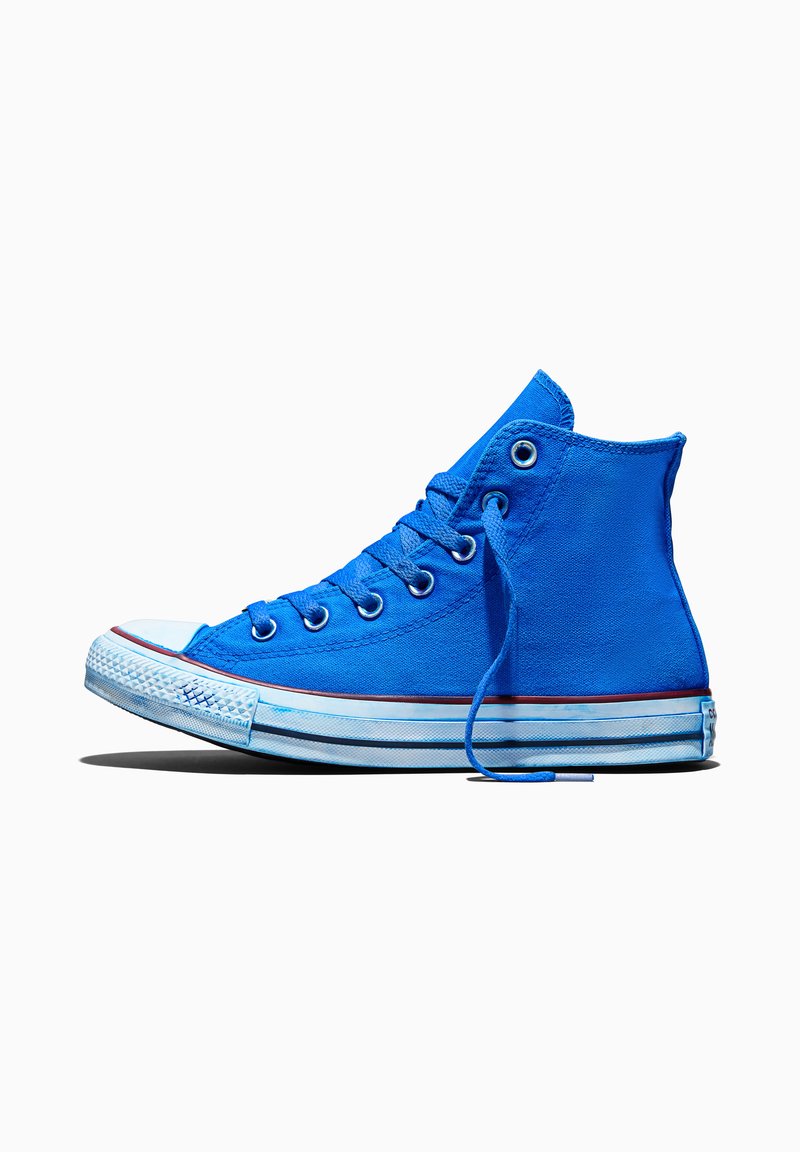 Blauer Canvas-Sneaker mit hoher Sohle, weißer Gummisohle, Metallösen und losem Schnürsenkel auf einfachem weißem Hintergrund.