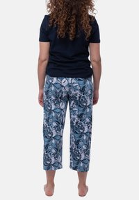 Navy lyhythihainen paita yhdistettynä lyhennettyihin housuihin, joissa on sininen kukkakuosi. Housuissa on rento istuvuus ja joustava vyötärö.