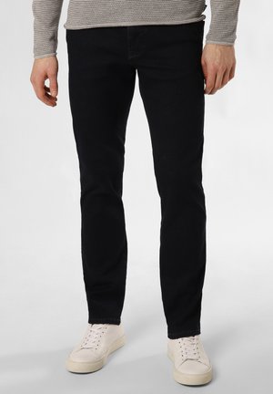 Dunkelblaue Slim-Fit-Jeans aus Denim mit subtiler Textur. Kombiniert mit weißen Low-Top-Sneakern mit Schnürverschluss.
