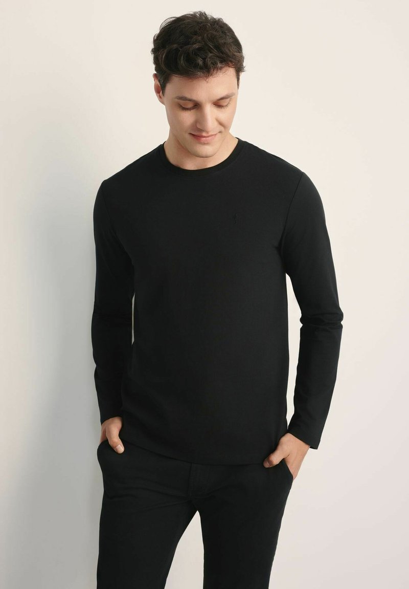 Czarna koszulka z długim rękawem, wykonana z bawełny, z okrągłym dekoltem, dopasowanym krojem i subtelnym logo na piersi.