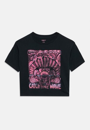 Svart kort T-skjorte med rosa grafikk av delfiner som hopper over en solnedgang, "ROXY" tekst over og "CATCH THE WAVE" under designet.