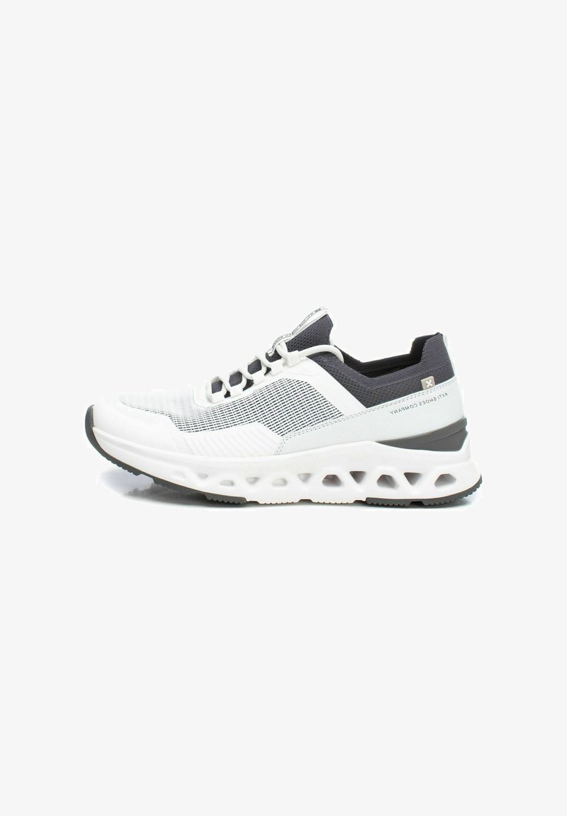 Zapatilla deportiva blanca y gris con parte superior de malla transpirable, detalles texturizados y suela acolchada con patrones recortados.