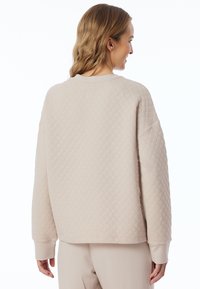 Beige gewatteerde sweatshirt met een ronde hals, lange mouwen en een gestructureerd ruitpatroon. Zachte stof met geribbelde manchetten.