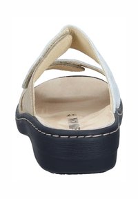 Beige avoinvarvassandaali, jossa on kaksi säädettävää remmiä, pehmustettu sisäpohja ja musta kumipohja ommelluilla yksityiskohdilla.