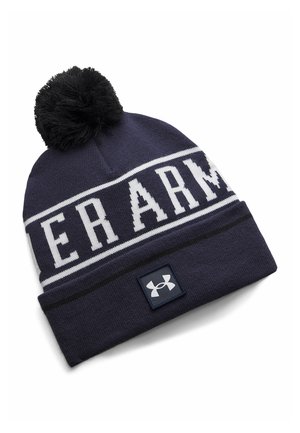 Navy blue knitted winter hat with black pom-pom, white "UNDER ARMOUR" text band, and Under Armour logo on the cuff.