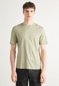 Lys olivengrøn bomulds t-shirt med rund hals og korte ærmer. Har et diskret "HUGO" logo på venstre bryst. Enkel design.