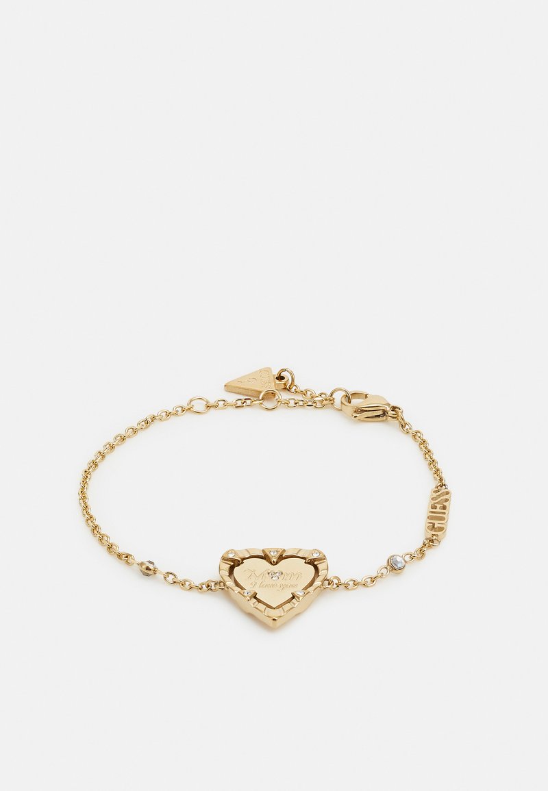 Pulsera de oro con un charm en forma de corazón grabado y cuatro pequeñas piedras transparentes, unida por una cadena con acentos grabados.