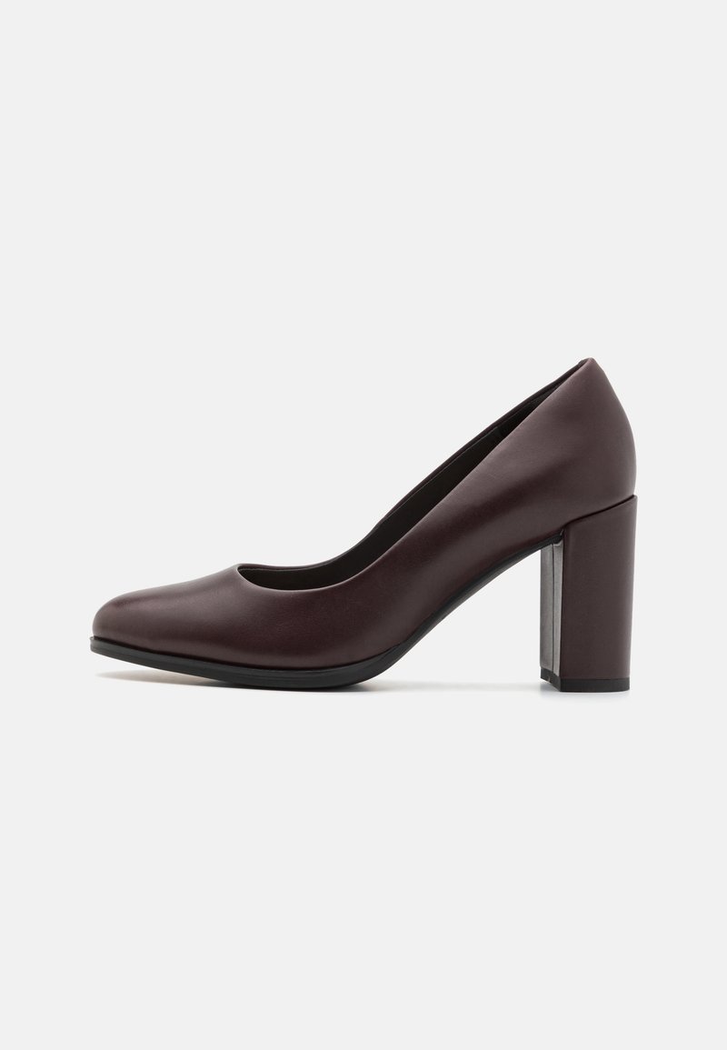 Zapatos de tacón alto de cuero burdeos con punta redonda, textura suave y tacón grueso; diseño minimalista sin patrones visibles.