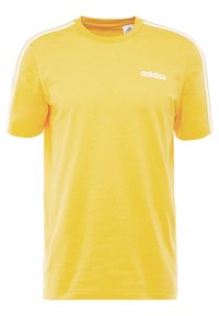 Camisa de algodón amarilla con mangas cortas, cuello redondo y logo blanco de Adidas en el pecho. Presenta rayas blancas a lo largo de las costuras de los hombros.