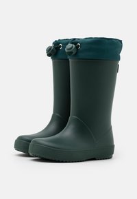 Bottes de pluie en caoutchouc vert avec une semelle texturée, une construction robuste et un col en tissu doux, teal foncé, avec un cordon de serrage.