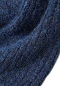 Tessuto di lana blu scuro con una superficie texture e pelosa. Il materiale presenta un motivo lavorato a maglia, che evidenzia le variazioni nello spessore del filato.