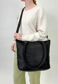Borsa a tracolla nera in pelle con texture liscia, manici doppi e tracolla regolabile. Presenta una chiusura con zip e dettagli hardware minimi.