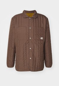 Brązowa pikowana kurtka z kołnierzem, zapięciem na napy, dwoma kieszeniami na piersi oraz logo The North Face na prawej kieszeni.