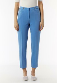 Pantalons ajustés bleu clair avec une coupe slim, dotés de deux poches avant et de deux boutons décoratifs à la taille. Texture de tissu lisse.