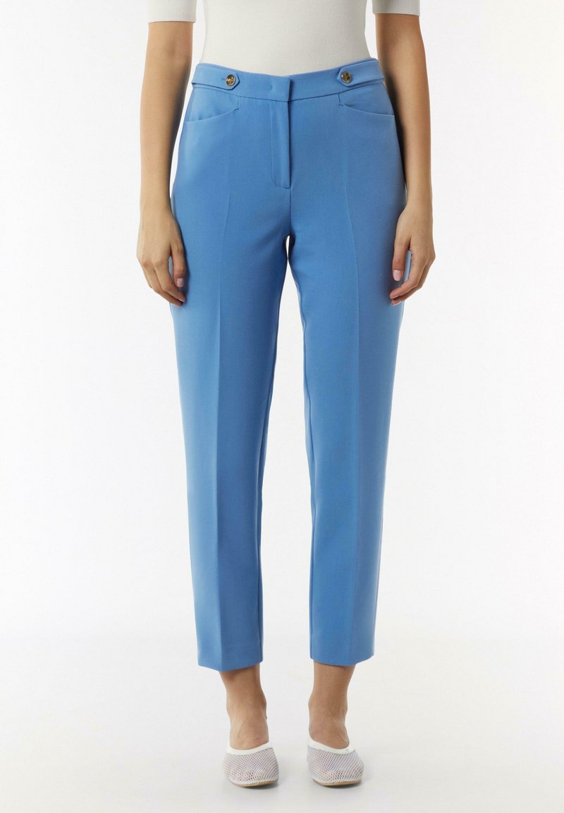 Pantalons ajustés bleu clair avec une coupe slim, dotés de deux poches avant et de deux boutons décoratifs à la taille. Texture de tissu lisse.