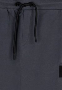 Grå sweatpants med snøre i taljen, der har en glat tekstur og elastisk talje. Inkluderer en lille sort logo detalje.