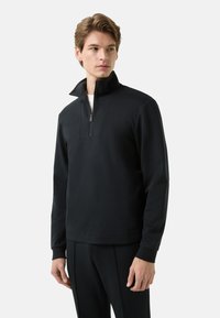 Czarna bluza zapinana na zamek wykonana z miękkiego materia�łu, z wysokim kołnierzem, długimi rękawami i minimalistycznym designem bez widocznych wzorów.
