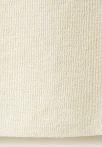Gros plan sur un tissu tricoté de couleur crème avec une texture douce, légèrement duveteuse et un motif de point régulier.