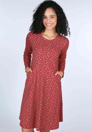 Rotes Blumenkleid mit langen Ärmeln, Rundhalsausschnitt und seitlichen Taschen. Es hat kleine rosa und blaue Blumenmuster auf einem strukturierten Stoff.