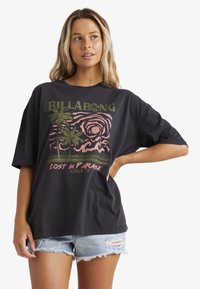 Sort oversized T-shirt med grafisk print af palmer og en sol i grønne og pink farver. Slidte denim shorts bæres til.