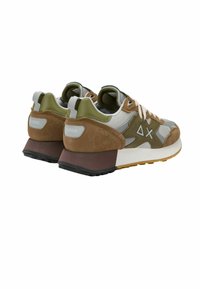 Baskets combinant du daim beige et du mesh gris avec des accents verts, une semelle robuste et une semelle extérieure noire texturée. Logo de la marque visible.