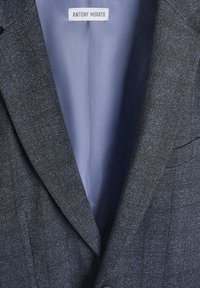 Blazer grigio con texture e rever a punta, con foderatura in satin blu chiaro. Etichetta interna con il marchio "ANTONY MORATO".