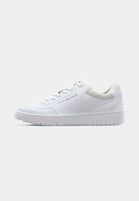 Baskets basses blanches avec lacets, semelle texturée et logo "Tommy Hilfiger" sur le côté, présentées du côté extérieur sur un fond uni.