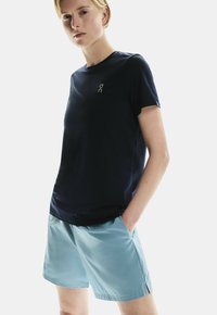 Tums zila sporta krekls ar īsām piedurknēm un apaļu kakla izgriezumu, apvienots ar gaiši ziliem šortiem. Smooth audums ar delikātu logotipa detaļu.