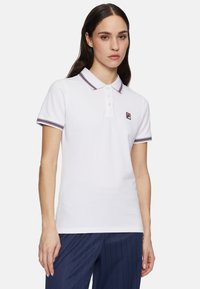 Weißes Poloshirt mit einer Dreiknopfleiste, kontrastierendem Kragen und Ärmelbündchen in Marineblau und Burgunderrot, mit kleinem Logo auf der Brust.