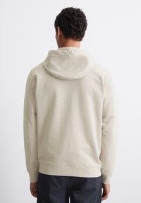 Hoodie beige chiaro in tessuto morbido, con cappuccio regolabile, polsini a coste e una vestibilità comoda, con dettagli minimi sul retro.