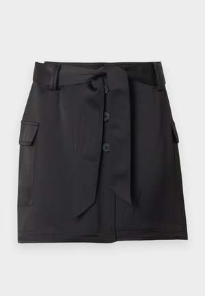 Fustă neagră până la genunchi, cu nasturi în față, buzunare laterale cu clapetă și o curea lată din material legată în talie.