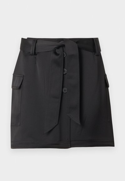 Μαύρη φούστα μήκους έως το γόνατο με κουμπιά μπροστά, πλαϊνές τσέπες με καπάκι και φαρδιά υφασμάτινη ζώνη δεμένη στη μέση.