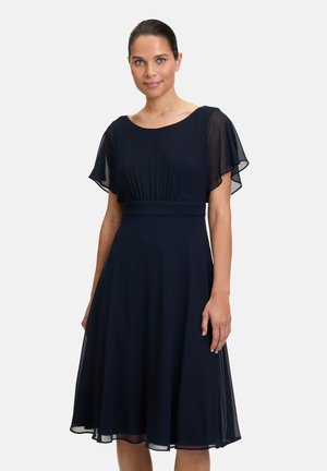 Marineblaues Kleid mit kurzen, durchsichtigen Flatterärmeln, einer gerafften Taille und einem fließenden Rock, der unter das Knie fällt. Glatte Stofftextur.