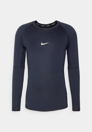 Navyblaues Langarmshirt aus leichtem Stoff mit Rundhalsausschnitt und kleinem weißen Nike-Logo auf der Brust. Nahtloses Design an den Ärmeln.