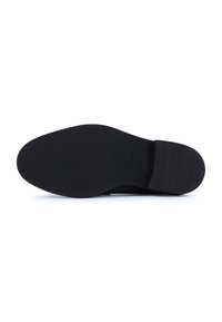 Suela de zapato de goma negra con una superficie lisa y plana, y sutiles surcos en el talón. Diseño minimalista, sin patrones ni texturas visibles.